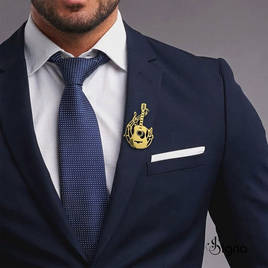 Man wearing a navy suit with a white shirt, blue tie, and gold lapel pin on a gray background.