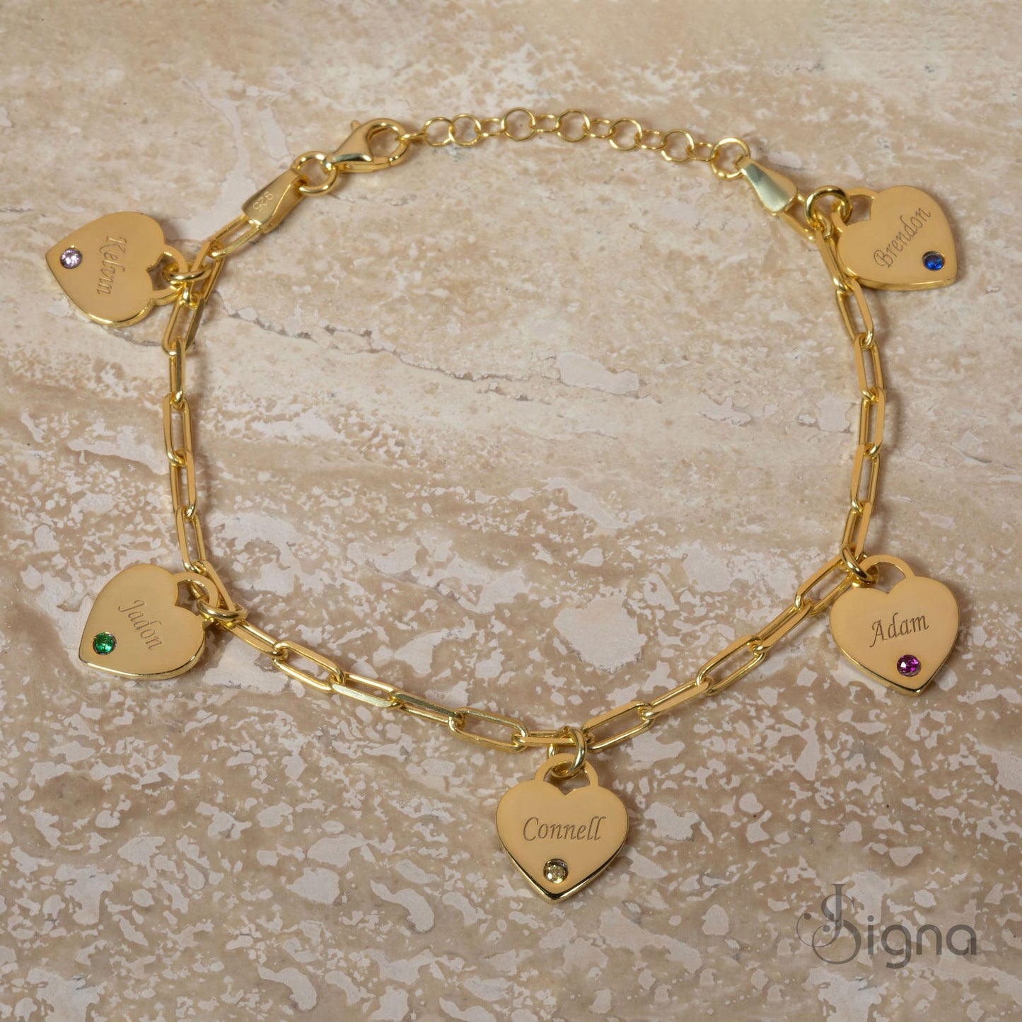 gold bracelet with heart-shaped name charms on a beige surface