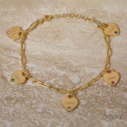 Gold bracelet with heart-shaped name charms on a beige surface