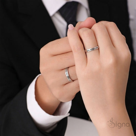 A close-up of a couple's hands joined together, wearing matching Signa™ personalized silver rings with custom secret messages engraved on the inside bands.