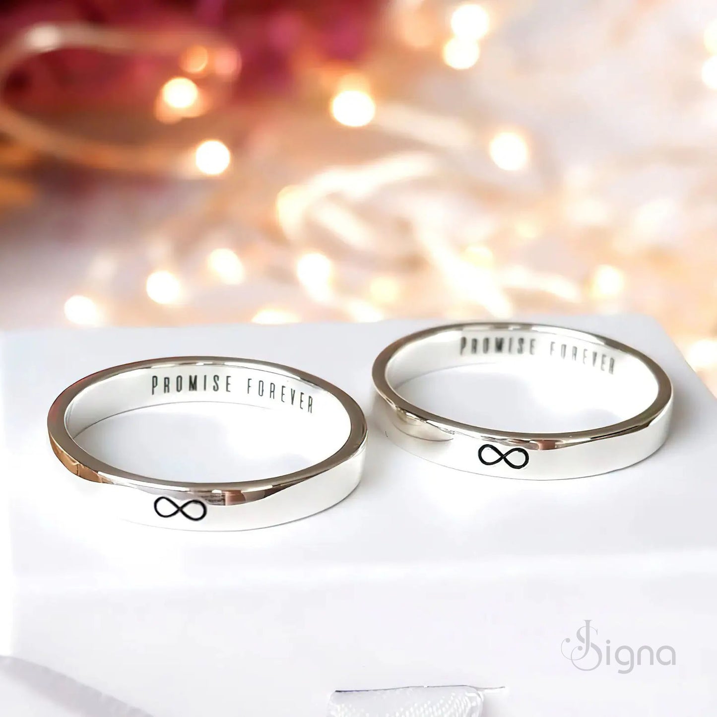 a close-up of a couple's hands joined together, wearing matching signa™ personalized silver rings with custom secret messages engraved on the inside bands.