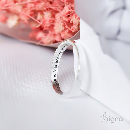 A close-up of a couple's hands joined together, wearing matching Signa™ personalized silver rings with custom secret messages engraved on the inside bands.
