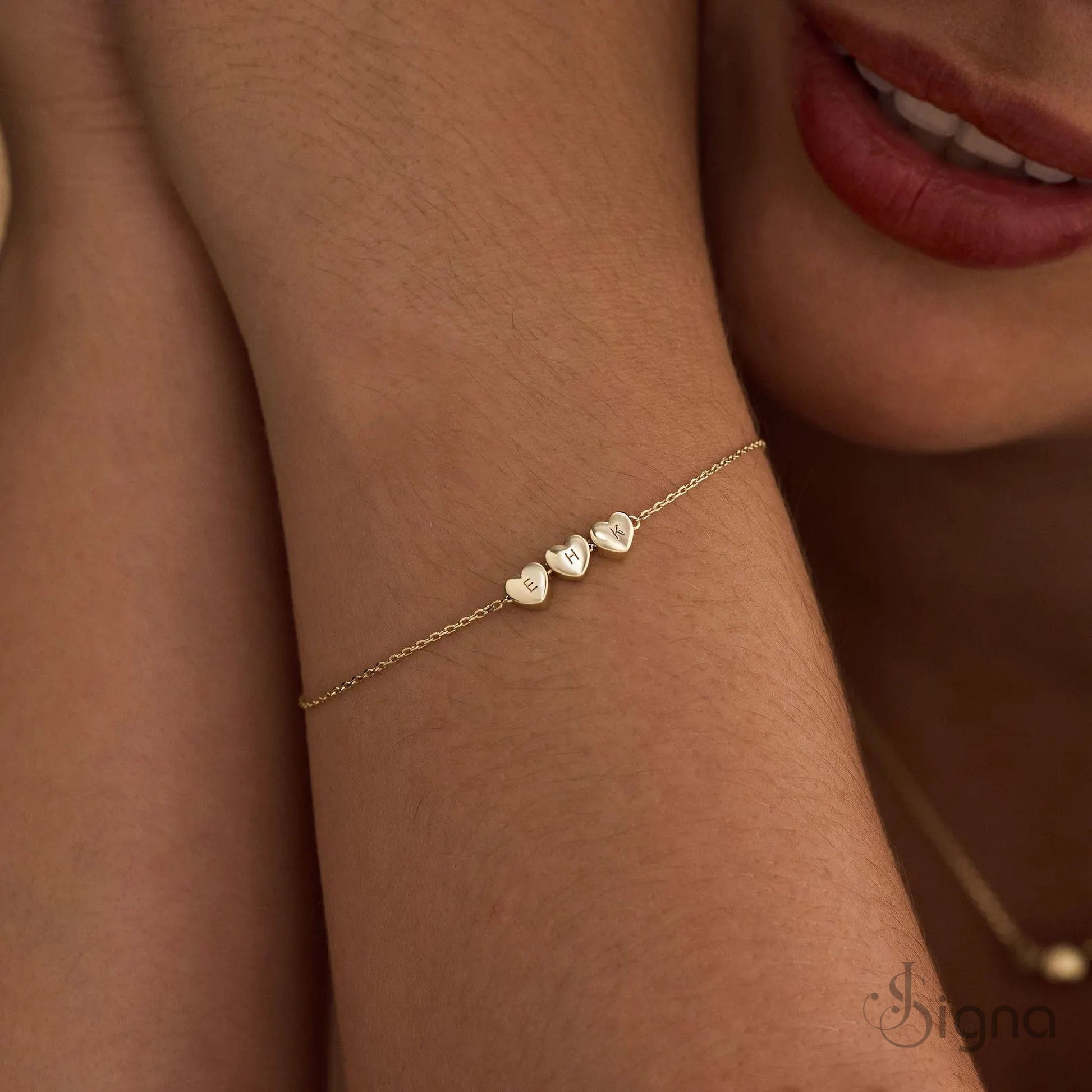 Gold bracelet with heart-shaped charms on a wrist, close-up shot.