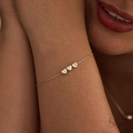 Gold bracelet with heart-shaped charms on a wrist, close-up shot.
