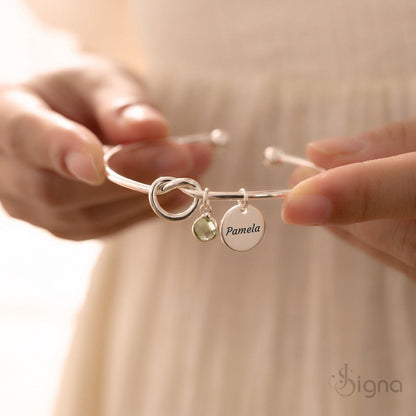 Engraved name disc bracelet with tie-knot design and birthstone charm